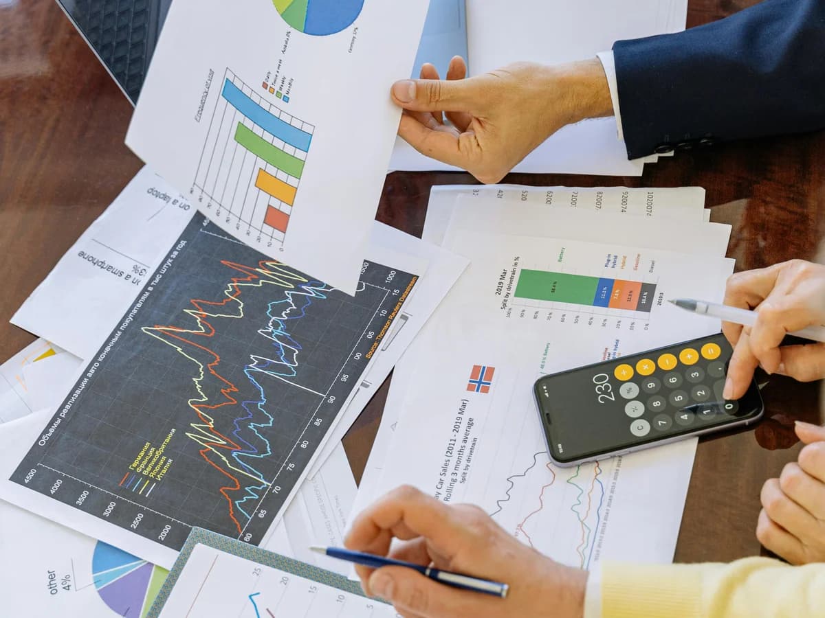 Hands reviewing performance charts on a desk with a calculator